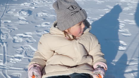 excited child girl enjoys sledding in plastic sleigh on snow at sunset pulled by father