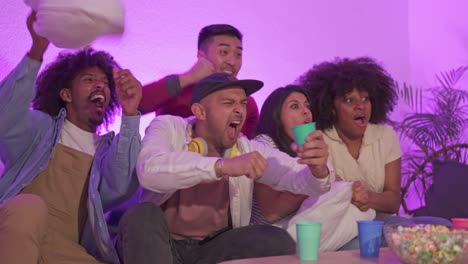 a group of diverse friends watching an exciting game and reacting intensely at home