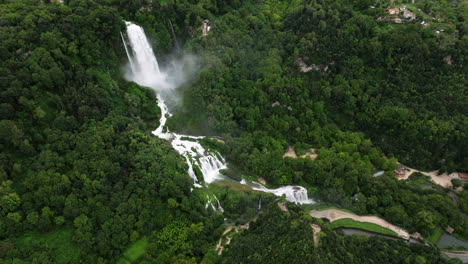 famous man-made waterfall surrounded by dense trees - marmore falls in umbria, italy