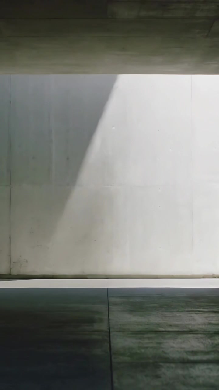 Vertical video: Projecting bright patch emerging from right slit and moving across gray wall, floor