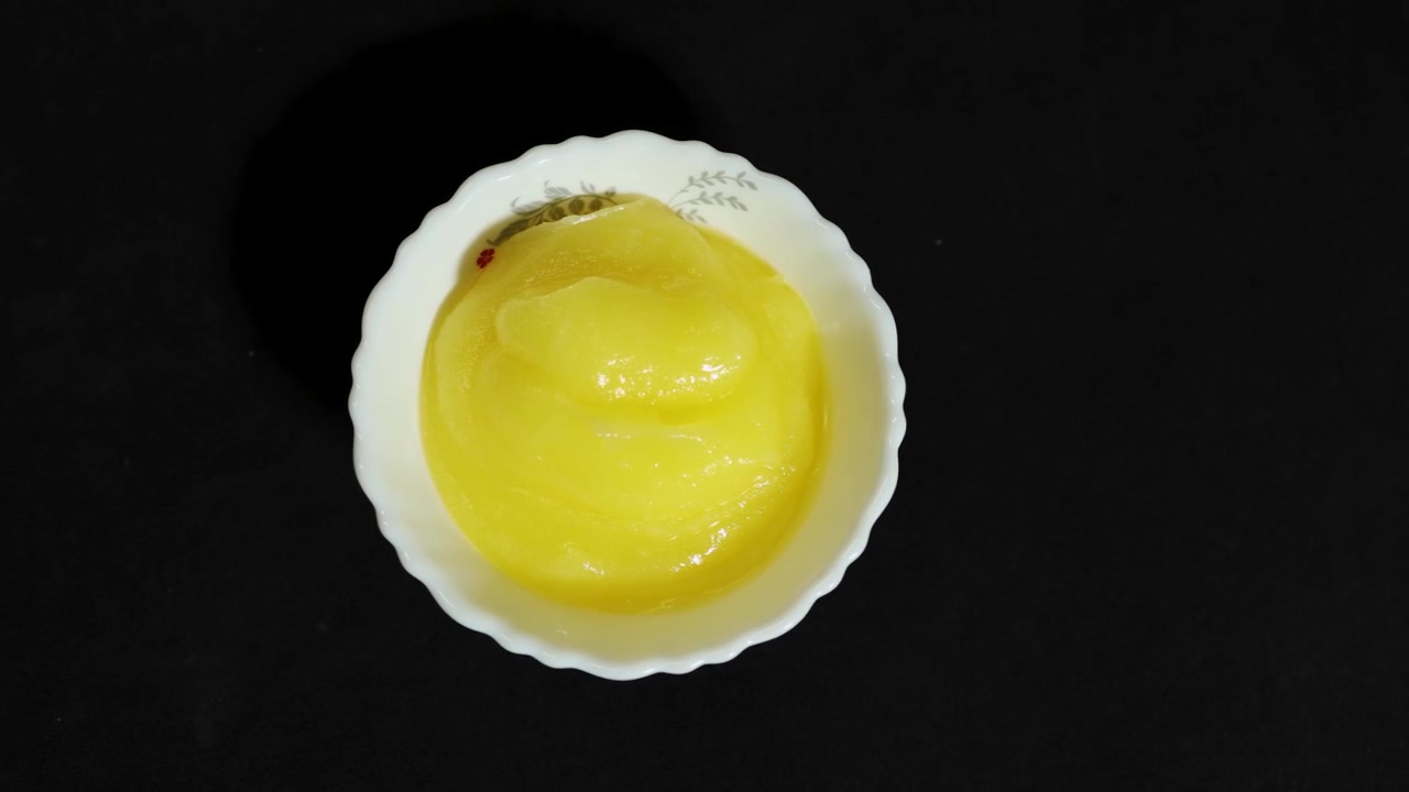 pure desi ghee in white bowl isolated on black background