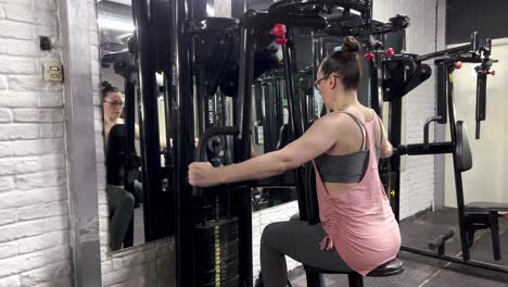 young woman doing arm muscle strengthening exercises in front of the mirror in the gym, doing arm strengthening movements