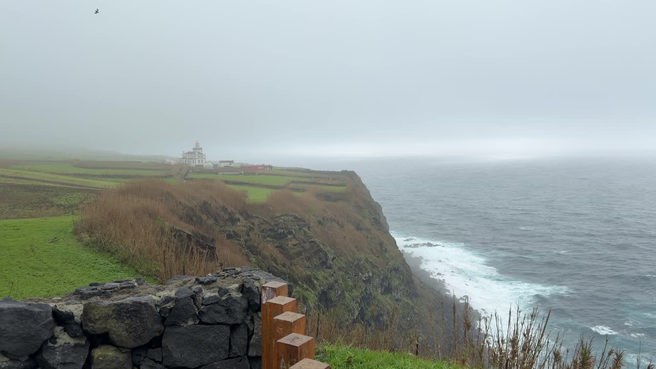 Mgliste klify wybrzeża z latarnią morską i widokiem na ocean na São Miguel, Azory, Portugalia.