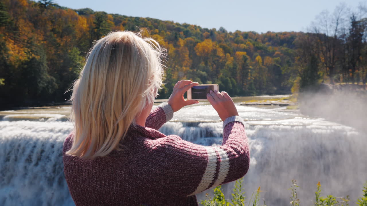 mujer fotografía cascada en bosque otoñal