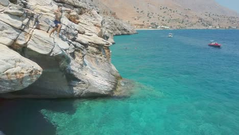 Young-fearless-man-having-fun-diving-inside-ocean-water-from-cliff