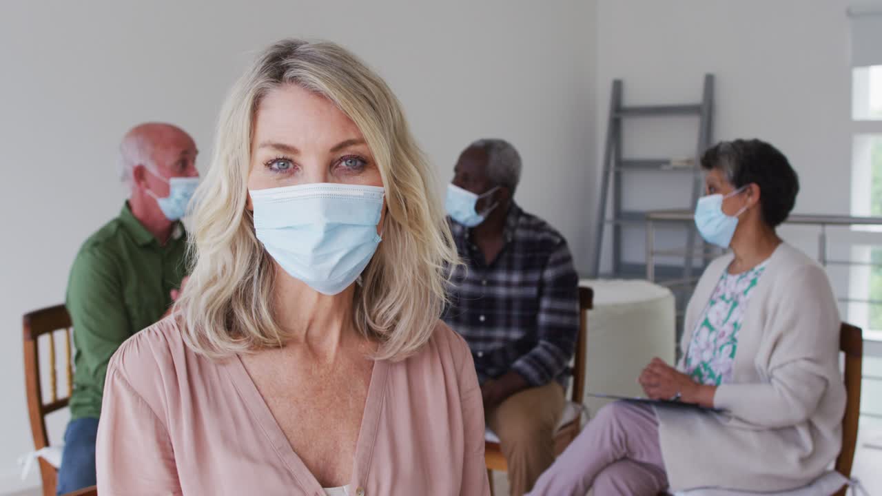 две разнообразные пожилые пары, сидящие в кругу, проводящие терапевтический разговор дома, глядя на камеру