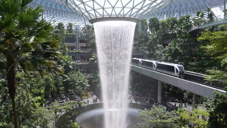 anti-gravedad de deformación del tiempo inverso movimiento artificial cascada interior rodeado de exuberante bosque verde dentro de un moderno centro comercial de lujo