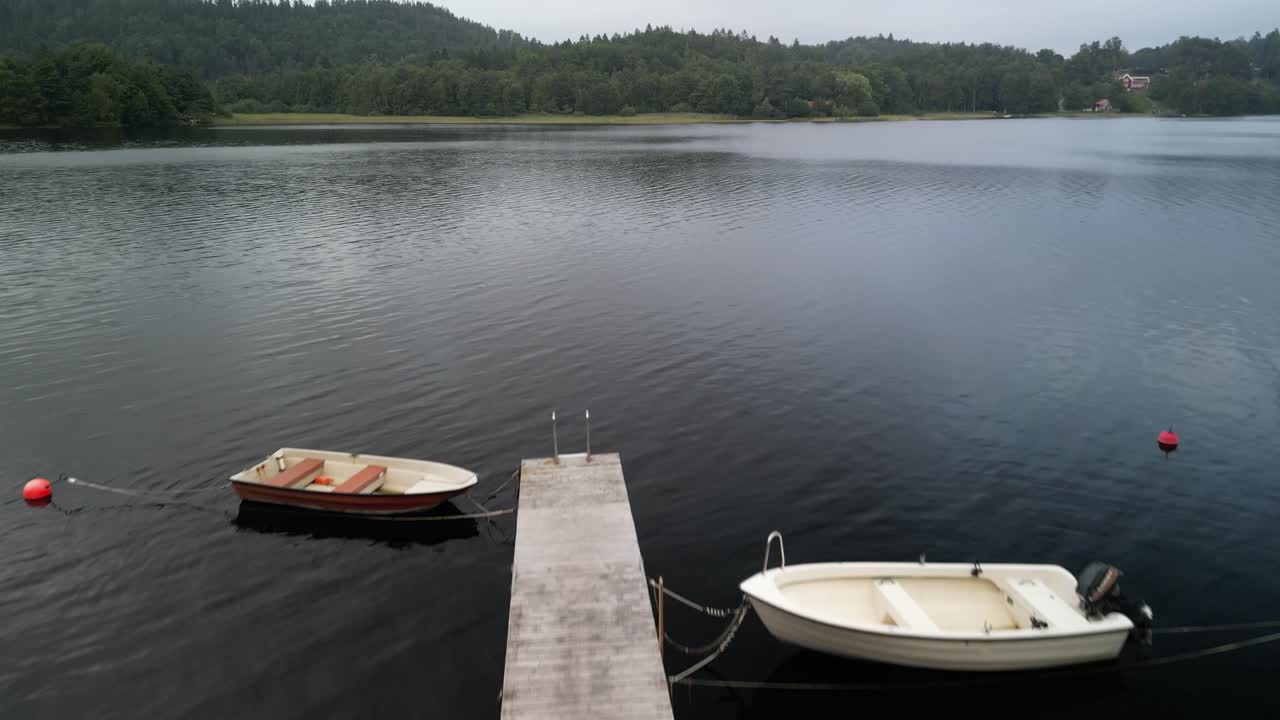 Små motorbåde fortøjet ved en søbro, luftoverflyvning, Sverige.