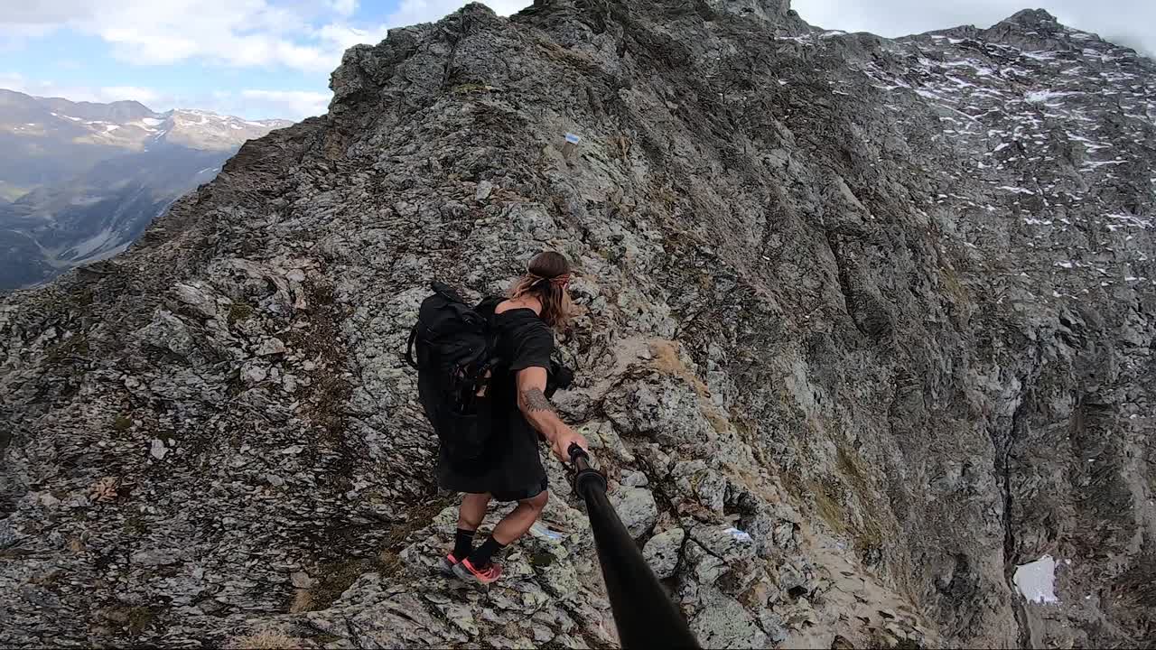 un hombre joven y en forma con cabello largo y tatuajes sonríe y estira su brazo y mano expresando alegría, felicidad y libertad