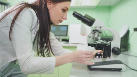 científica que trabaja con el microscopio en un laboratorio
