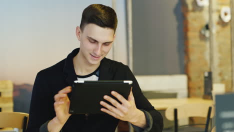 Stylish Man In A Suit Uses A Tablet In Cafe