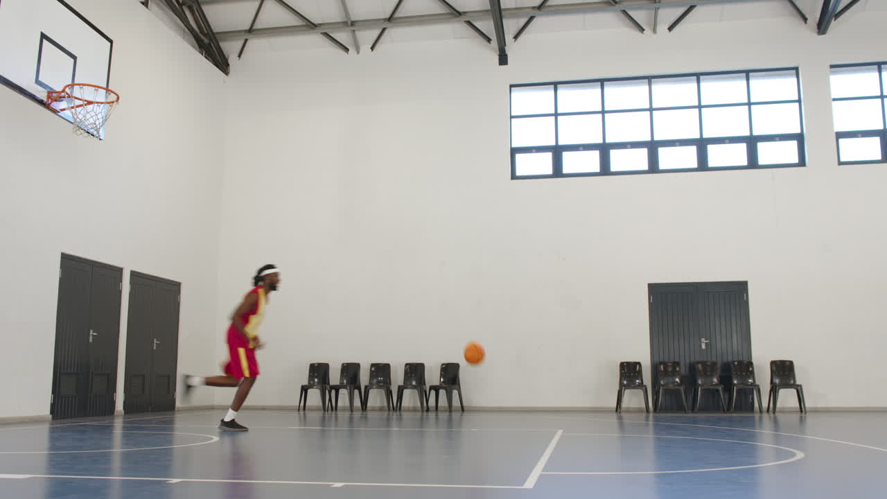 African american male basketball player playing basketball, running in gym