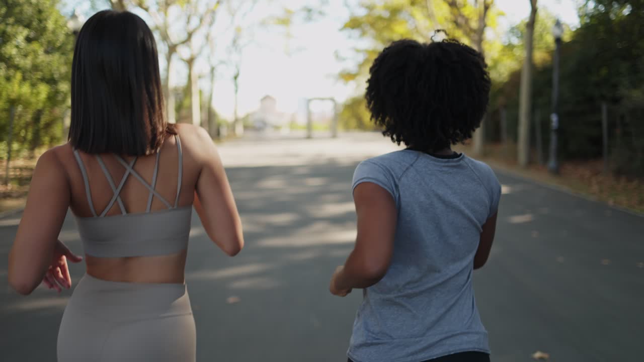 Due donne che fanno jogging e parlano su un sentiero alberato del parco