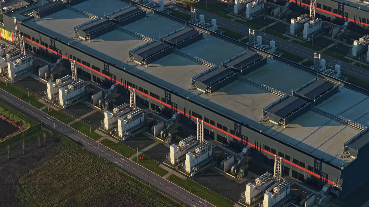 Luftfoto af et moderne AI-datacenter med køletårne ved solopgang.