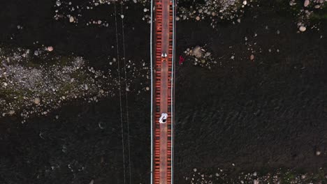 Dos-Turistas-En-Medio-Del-Puente-Colgante-Con-Agua-De-Río-Tranquila-Que-Fluye-Debajo--Guinsaugon,-Sur-De-Leyte,-Filipinas