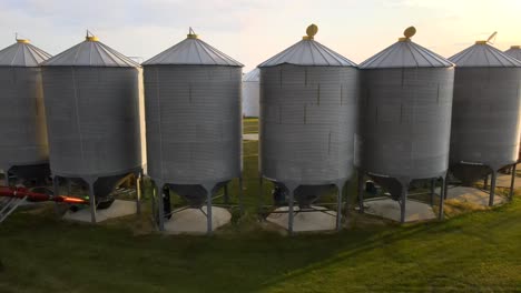 4k drone en orbite autour de plusieurs grands bacs de grain debout en demi-cercle sur une petite ferme familiale exploitée dans la campagne américaine