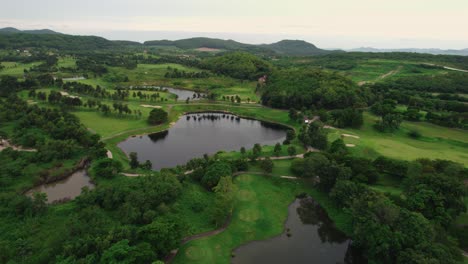 flying over a beautiful green park with lakes and hills