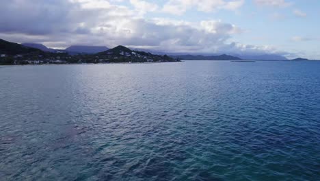 Imágenes-De-Drones-A-Través-Del-Océano-Pacífico-Azul-Profundo-Cerca-De-La-Playa-De-Lanakai-Oahu-Hawaii-Con-Playa-De-Arena-Blanca-Y-Residencias-Ubicadas-Entre-Las-Montañas-De-La-Selva-Tropical-Y-El-Océano