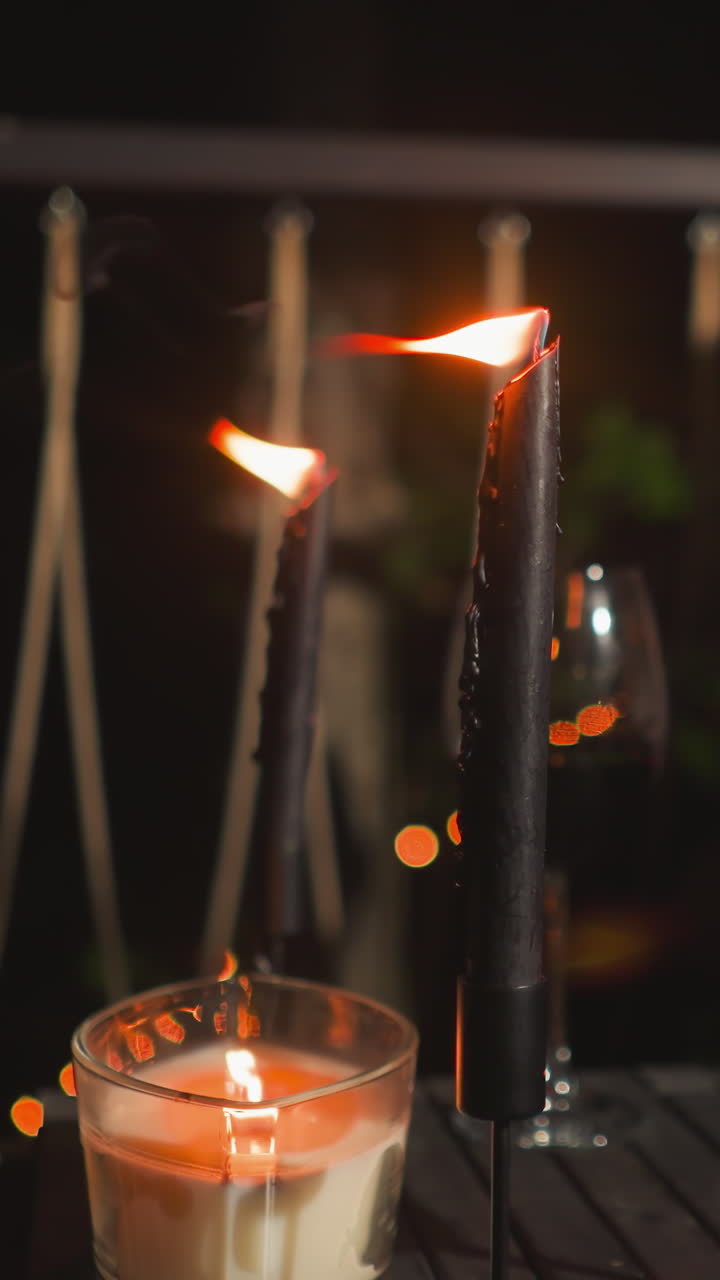 Burning stylish candles and wineglasses on table at romantic date closeup. Delicious drinks and intimate atmosphere accessories on terrace. Dinner for two