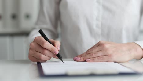 businesswoman examines document and puts signature closeup