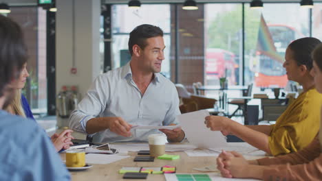 business team having meeting sitting around table discussing document in modern open plan office