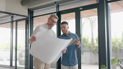 two diverse mele architects with digital tablet and a plan discussing at office