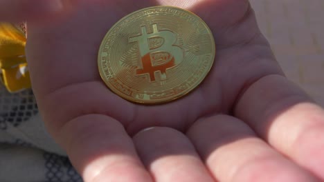 taking a bitcoin token from the palm of the hand