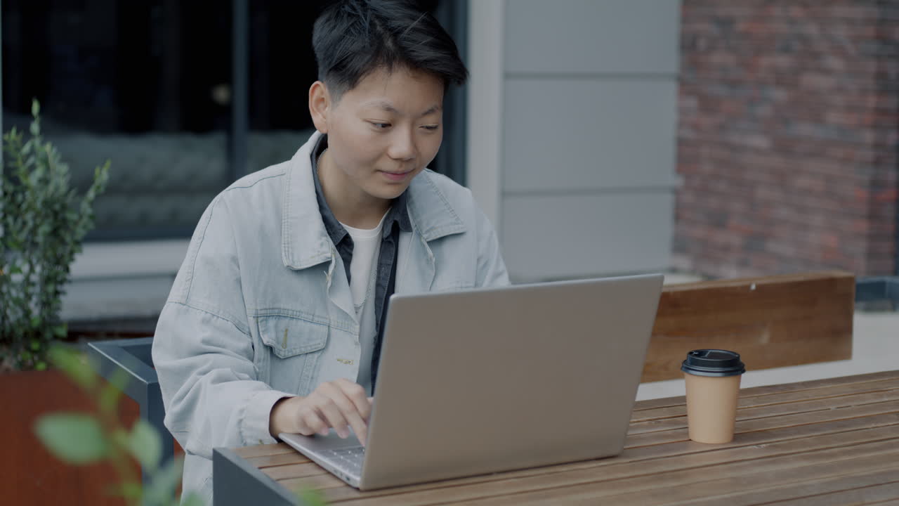 Woman working on laptop outdoors at a cafe