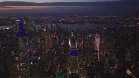 Various-colour-lights-on-skyscrapers-in-midtown.-Aerial-panoramic-footage-of-evening-cityscape.-Manhattan,-New-York-City,-USA