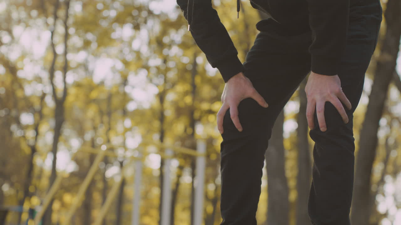 Man experiencing knee pain after exercise in a park