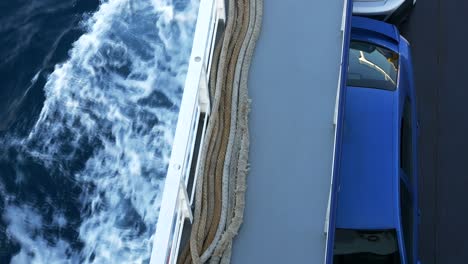 view of the deck of a car-carrying ferry and foamy waves trailing behind the hull