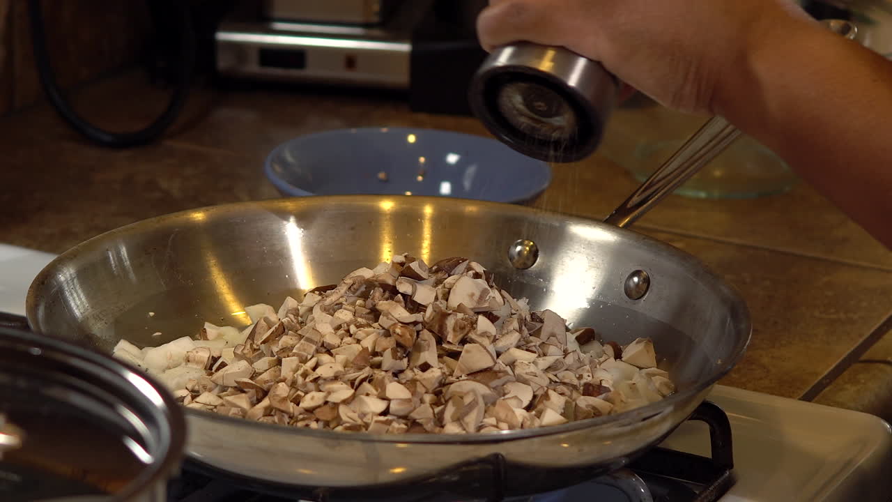 moler pimienta sobre champiñones y cebollas en una sartén, cerrar