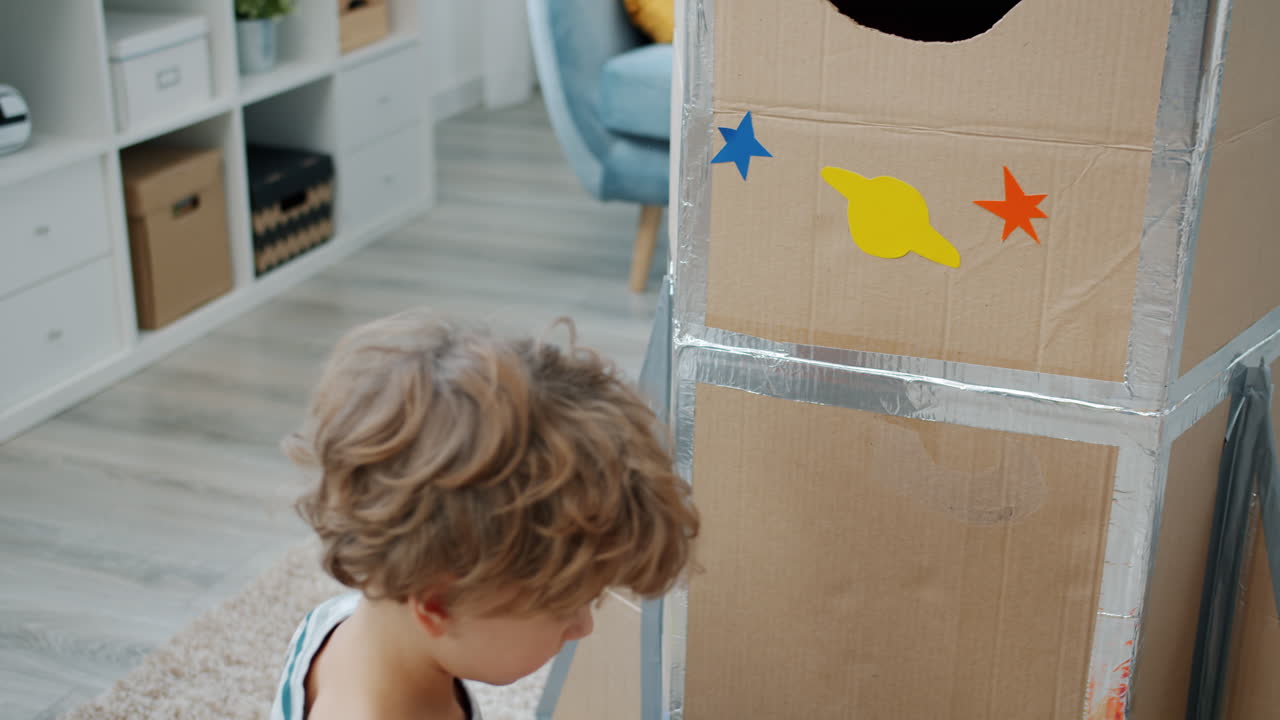 Child Playing with Cardboard Rocket