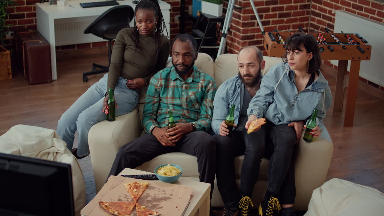 Multiethnic group of friends clinking beer bottles at house party