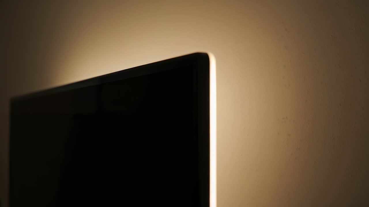 Wall display entering standby while LED strip emitting warm halo, creating home tech mood