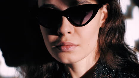 mujer elegante con gafas de sol en la iluminación sombría