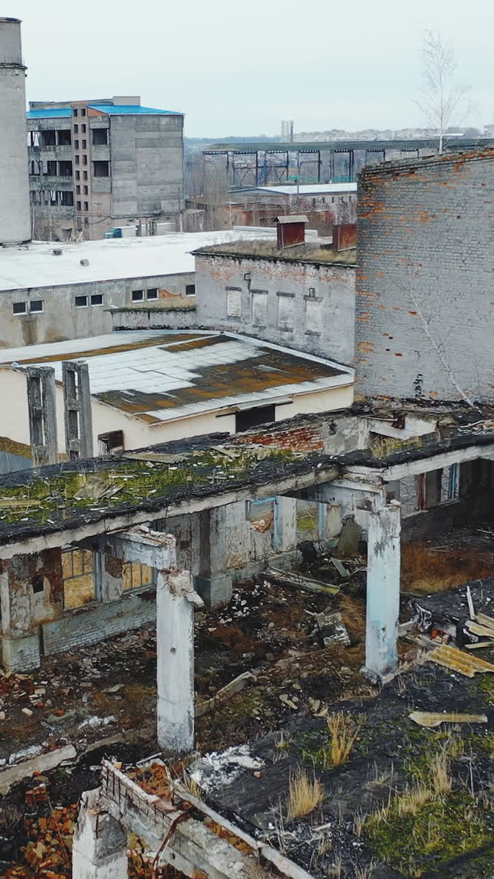 Gray abandoned destroyed industrial zone. Ruins of houses and workshops. Ukraine. Vertical video. Aerial view