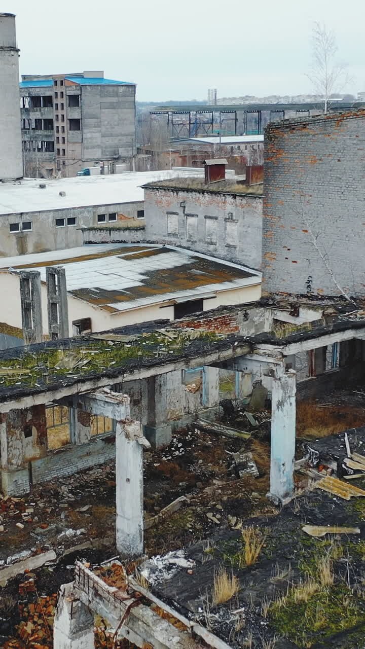 Zona industriale grigia abbandonata e distrutta. Rovine di case e officine. Ucraina. Video verticale. Vista aerea.
