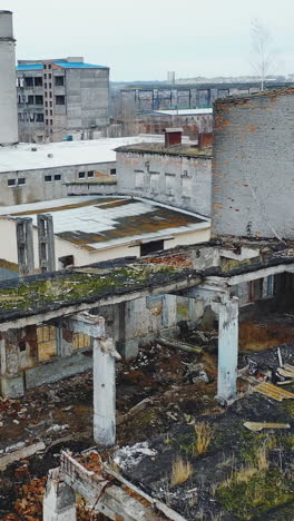 gray abandoned destroyed industrial zone. ruins of houses and workshops. ukraine. vertical video. aerial view