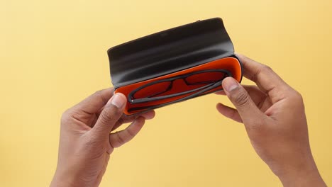manos sosteniendo gafas en un estuche negro