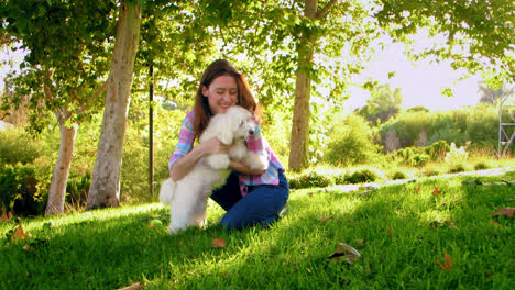 una mujer joven le da a un perro peludo blanco un gran abrazo