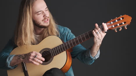 caucasian young man playing guitar and singing on camera.