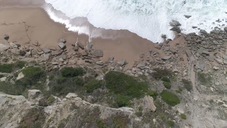 arriba hacia abajo los acantilados y la línea costera con las olas rompiendo
