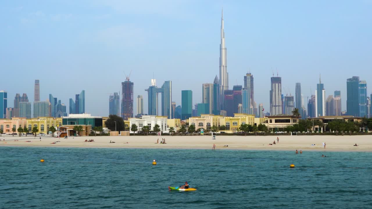 아랍 에미레이트 두바이를 배경으로 도시의 고층 빌딩이 있는 해변에서 카약을 타는 사람