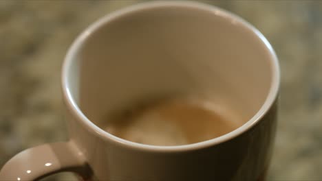 close up of sweetener dripping in the coffee inside a mug