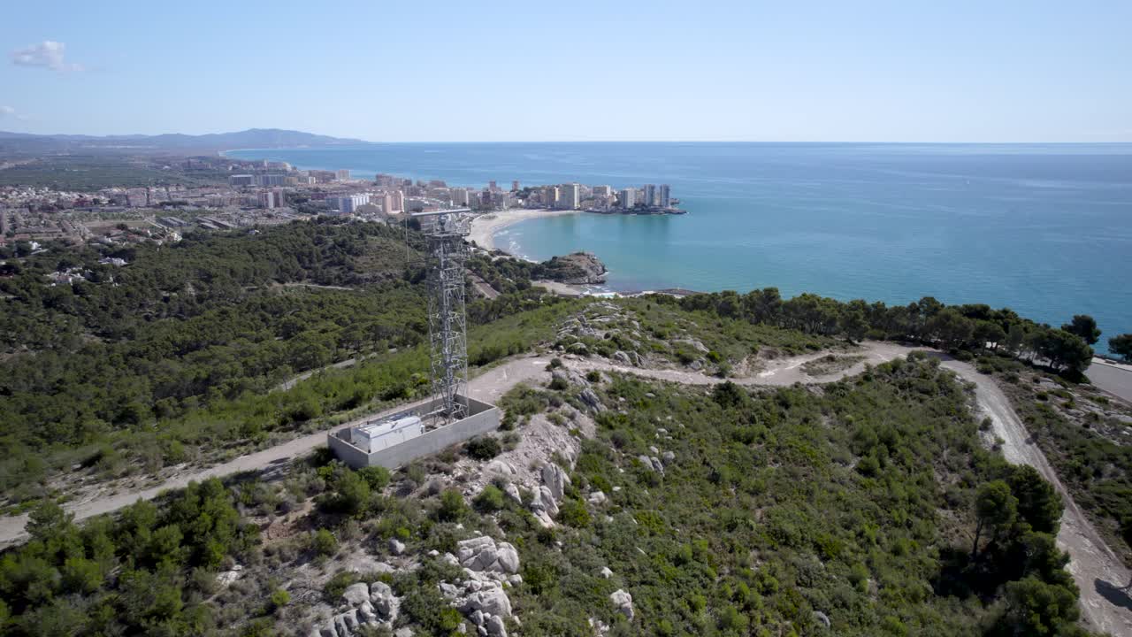 vuelo de un avión no tripulado de 4k junto a un radar marítimo giratorio en la cima de la colina hacia el azul mar mediterráneo en oropesa del mar, castellon, españa