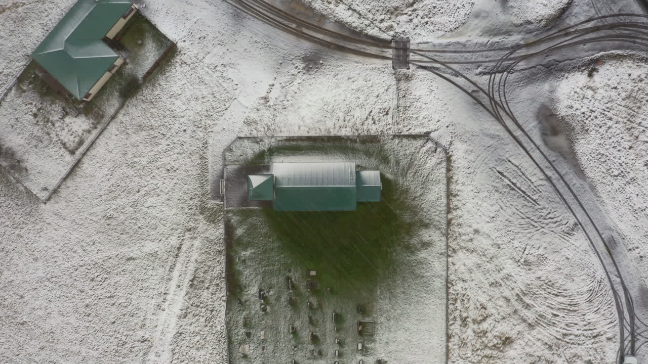 Aerial: Top down shot of remote Church in Iceland during snowstorm