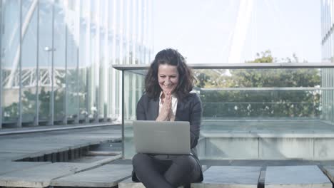 happy excited businesswoman using laptop outside, looking at display, getting good news, making winners gestures and looking at camera