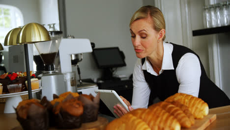 Smiling-waitress-using-digital-tablet-at-counter