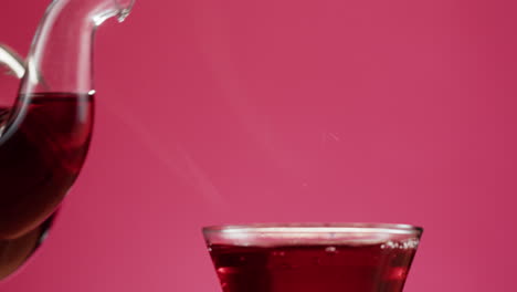 red tea poured from teapot into glass cup